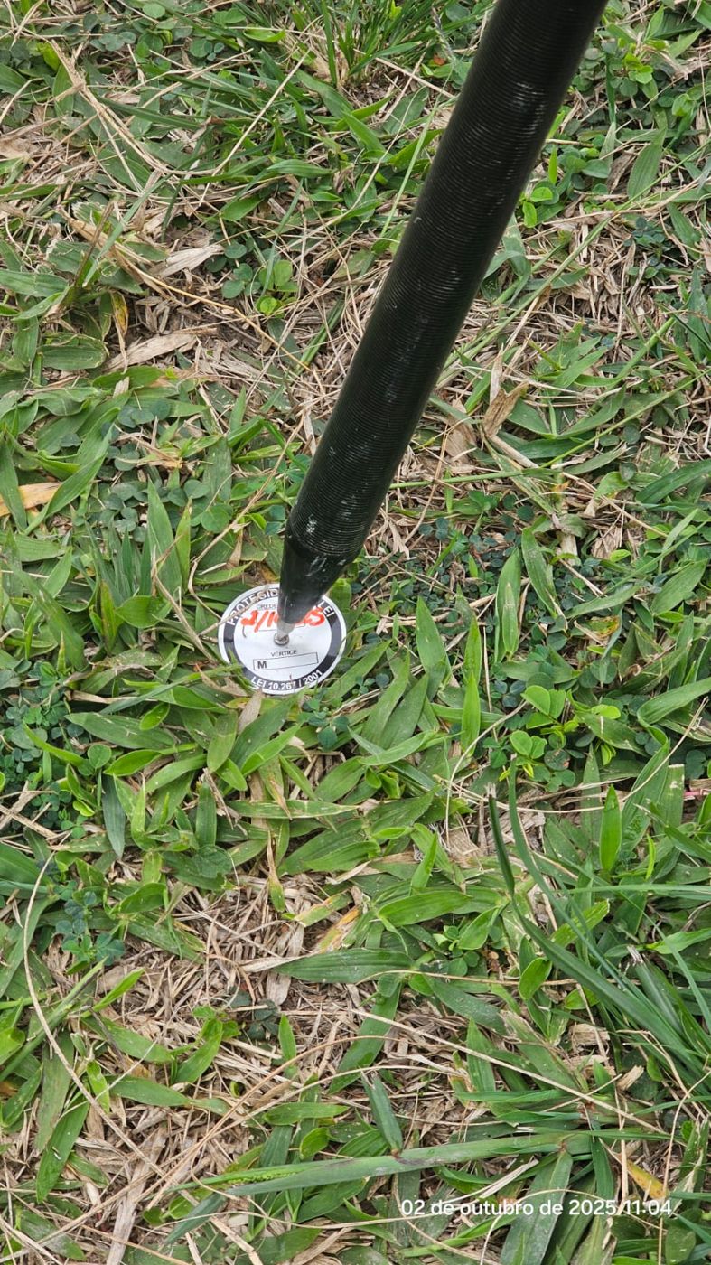 Bastão do receptor GNSS posicionado sobre marco de vértice em levantamento topográfico